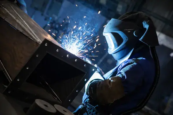Soudure métallique en atelier avec casque de protection et gerbes d’étincelles